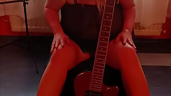 Eine In Dessous Gekleidete Milf Masturbiert Mit Ihren Größten Titten In Der Nähe Der Gitarre